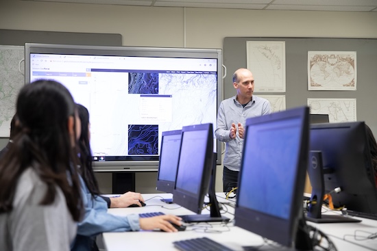 Instructor teaching students with a map displayed on a large screen.
